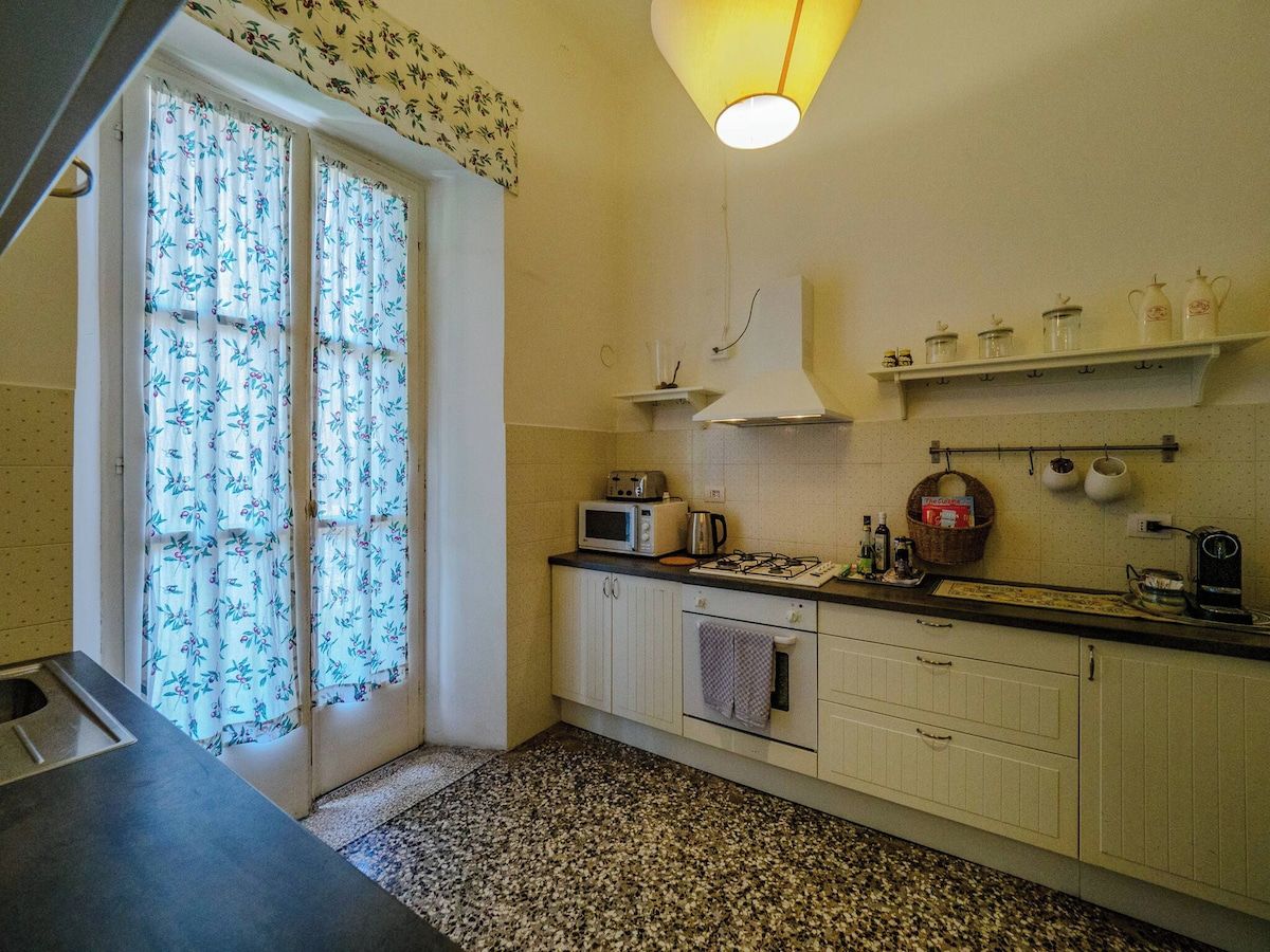 A kitchen with a microwave, toaster, kettle, and a gas stove.