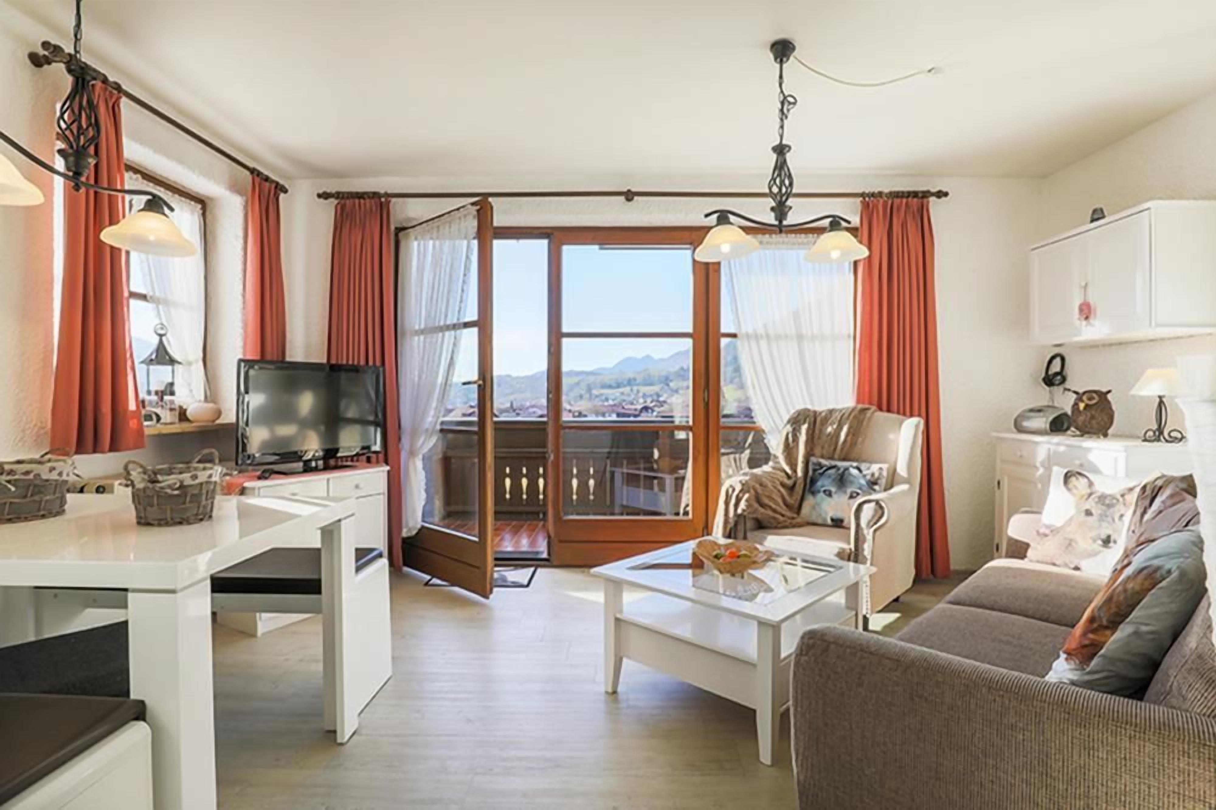 Een woonkamer met een televisie, een bank, een salontafel en uitzicht op een balkon.