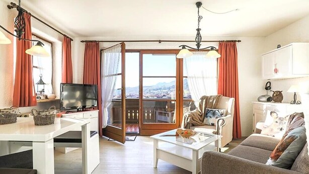 Uma sala de estar moderna com televisão, mesa de jantar, sofá e varanda com vista.