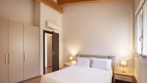 Ein Schlafzimmer mit Bett, Nachttischen, einem Kleiderschrank und einer Klimaanlage.