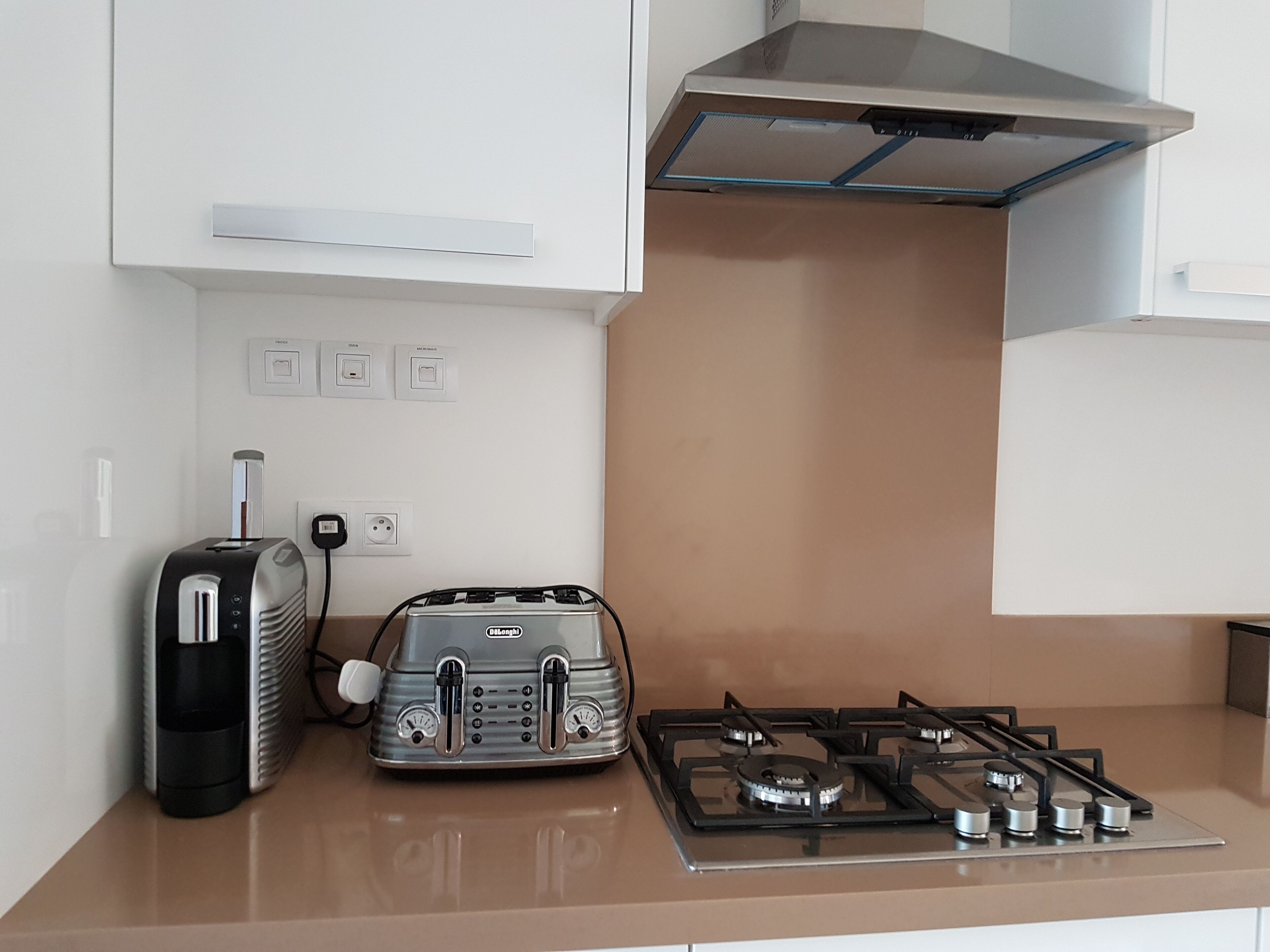 Een keuken met een gasfornuis, een broodrooster en een waterkoker.