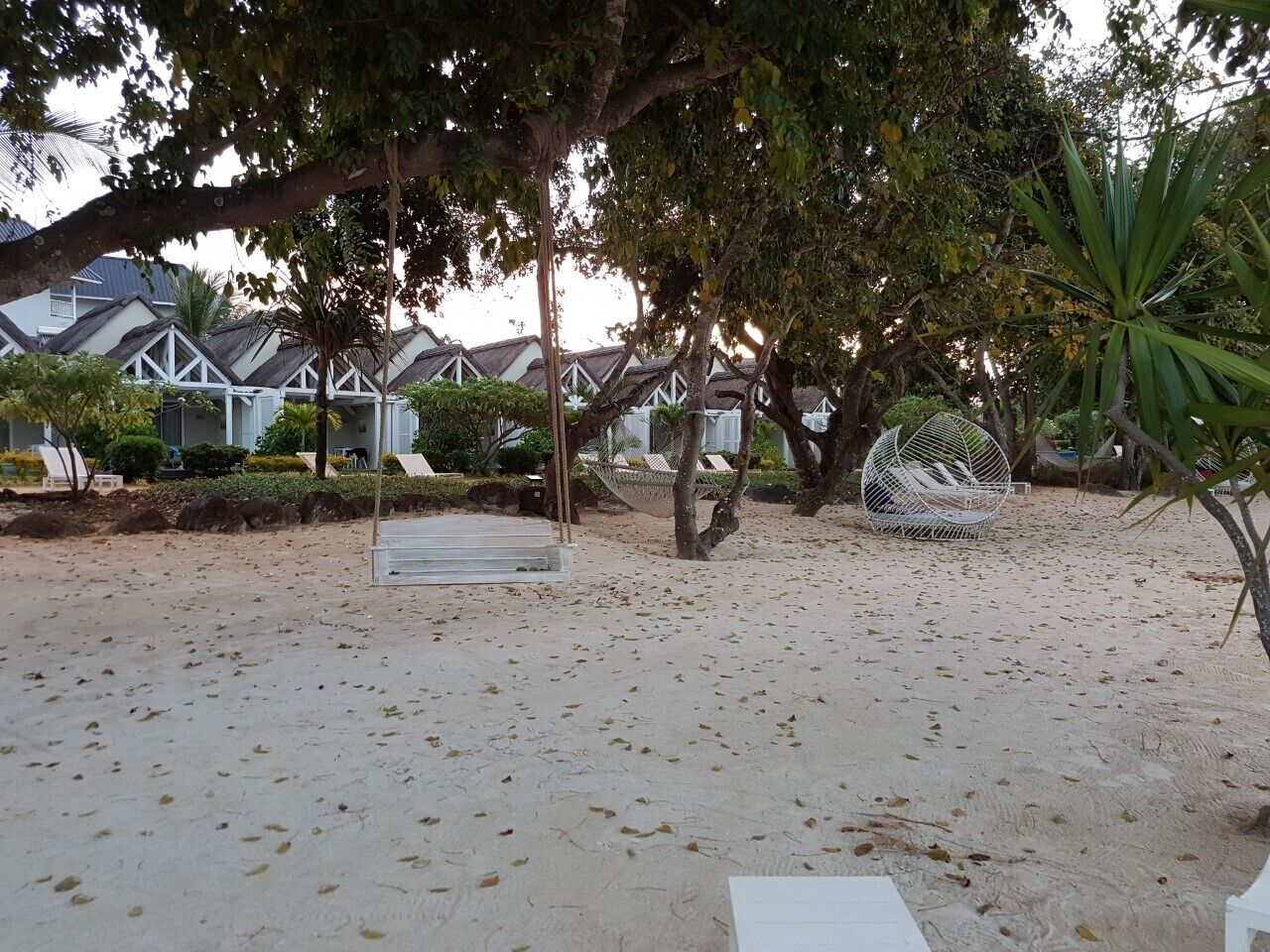 Un espace de plage aménagé avec un fauteuil suspendu, un hamac et une petite piscine.