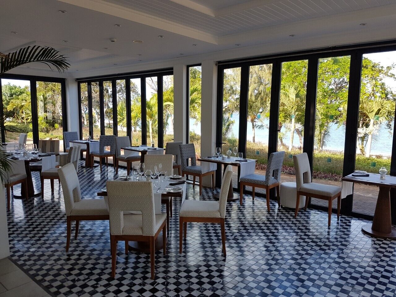 A dining area with tables and chairs, large windows, and a checkered floor.