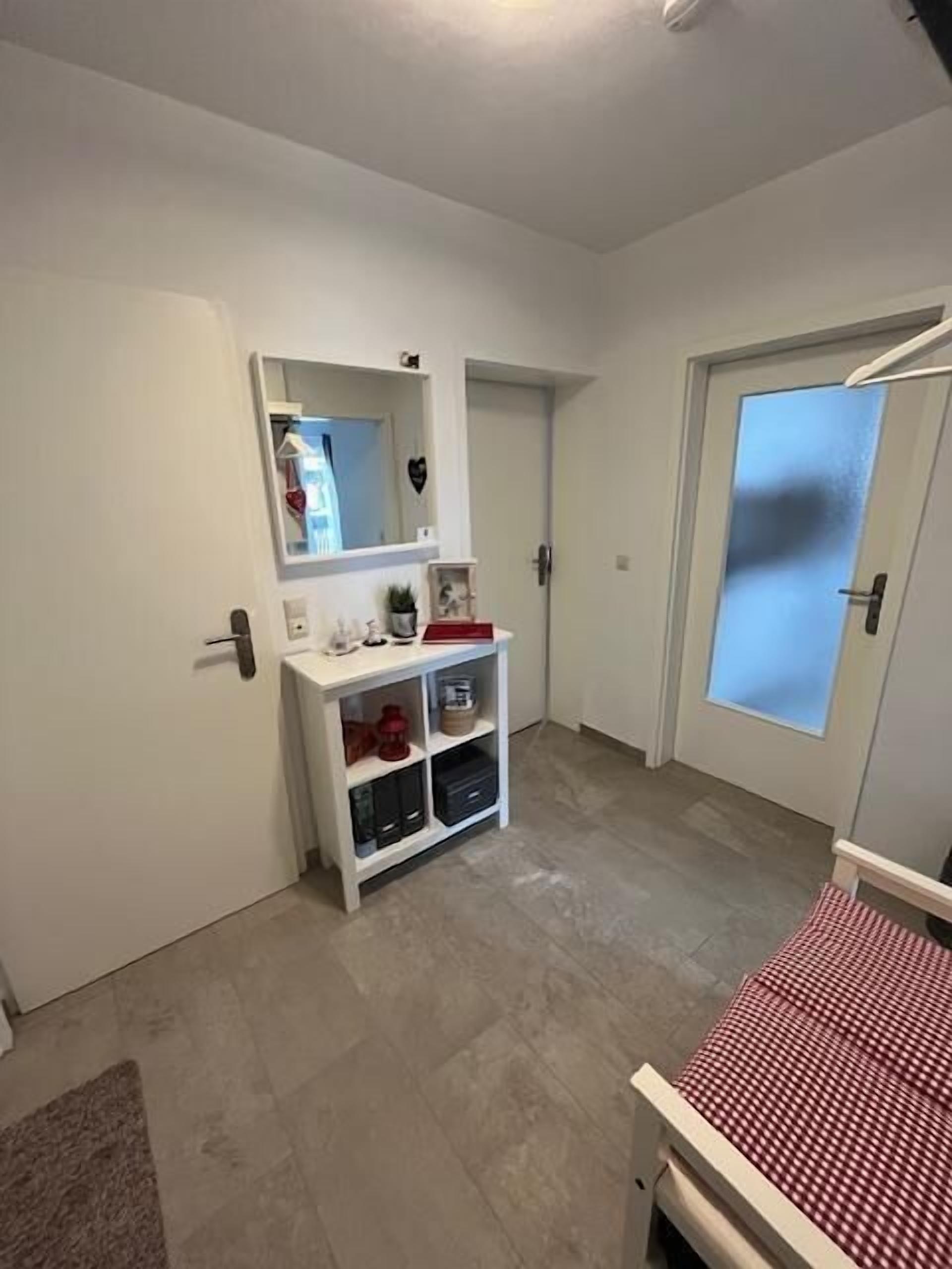 A hallway with a white console table, a mirror, and a door with frosted glass.