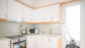 Moderni keittiö, jossa on valkoiset kaapit, sisäänrakennettu uuni, mikroaaltouuni ja pesuallas.