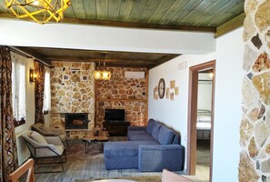 A cozy living room with a stone wall, a fireplace, a sofa, and a television.