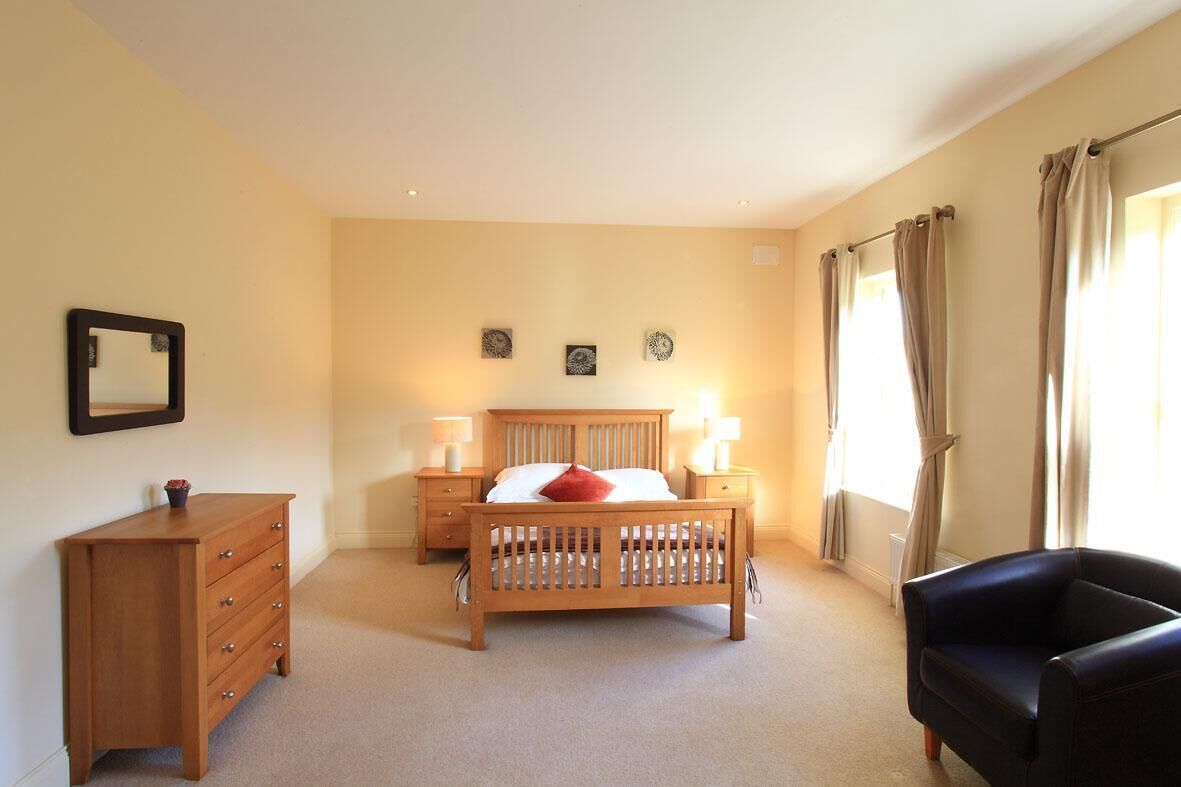 Une chambre à coucher avec un lit en bois, une commode, une chaise et deux tables de chevet avec des lampes.