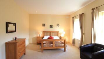 Une chambre à coucher avec un lit en bois, une commode, une chaise et deux tables de chevet avec des lampes.