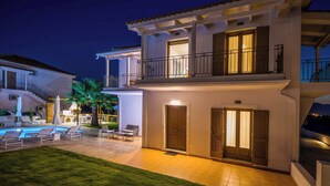 A two-story house with a balcony, a swimming pool, and a well-maintained lawn.