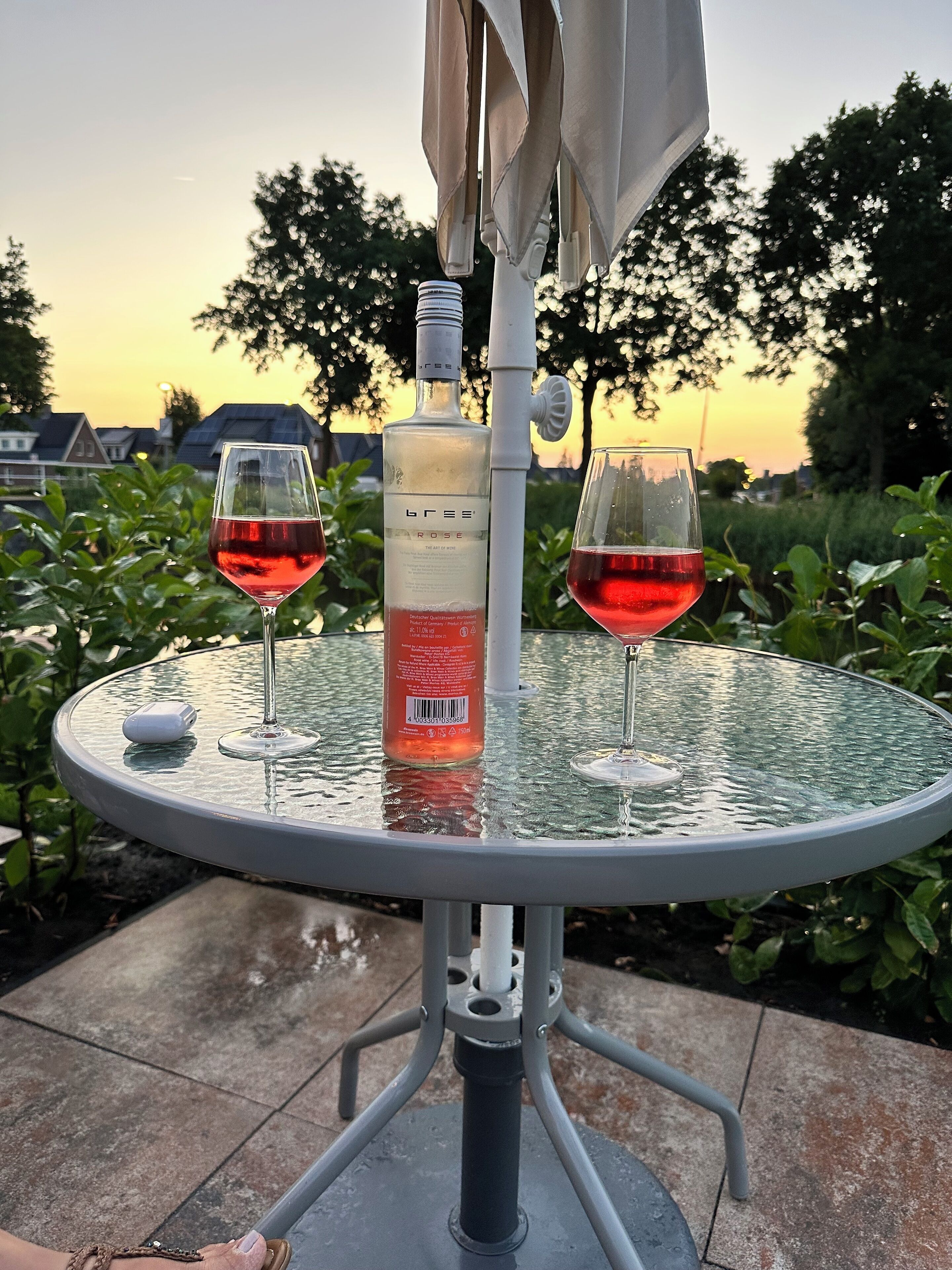 Une table ronde en verre, avec deux verres à vin et une bouteille de vin.