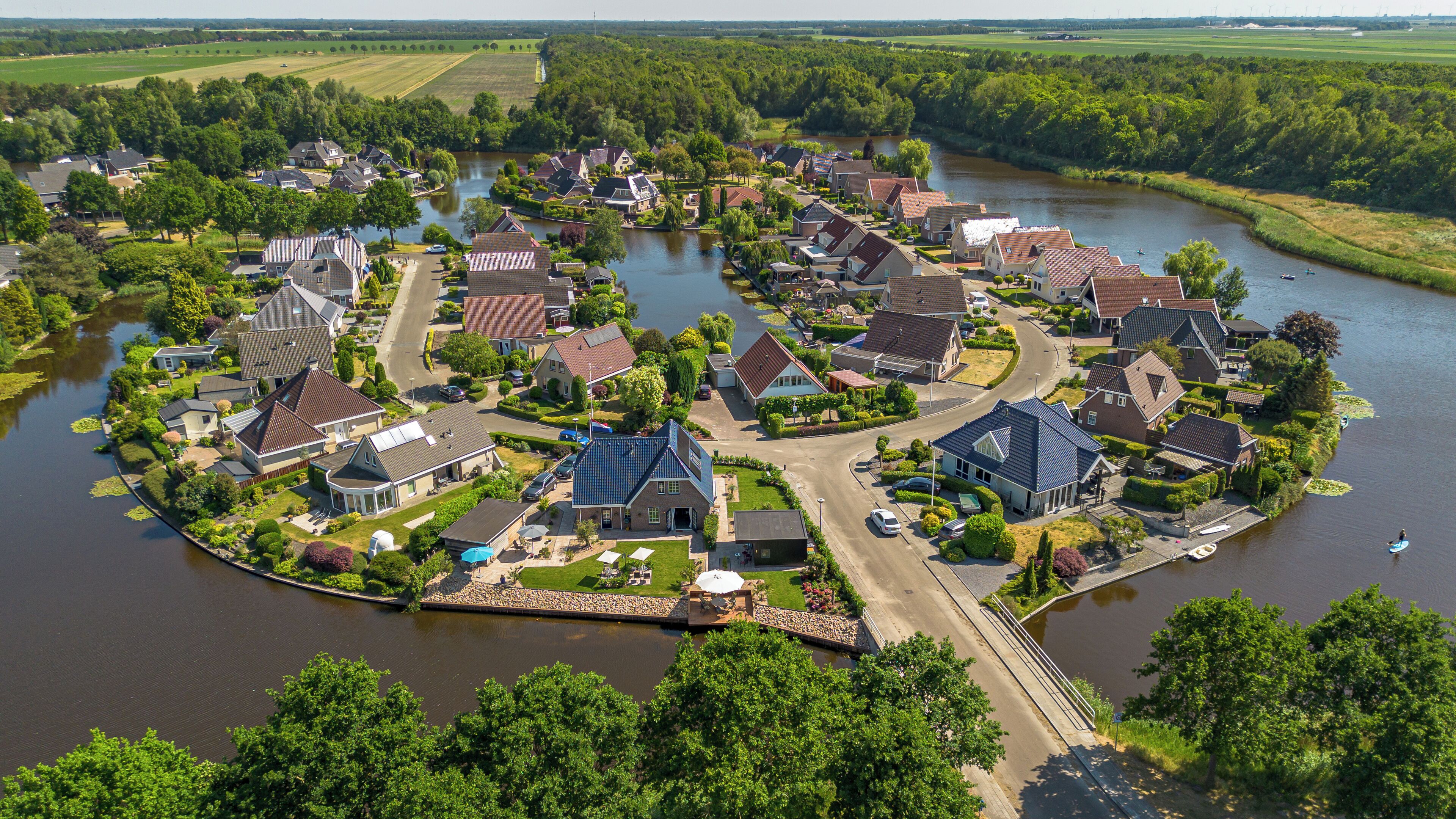 A riverside residential area with houses, a dock, and a bridge.