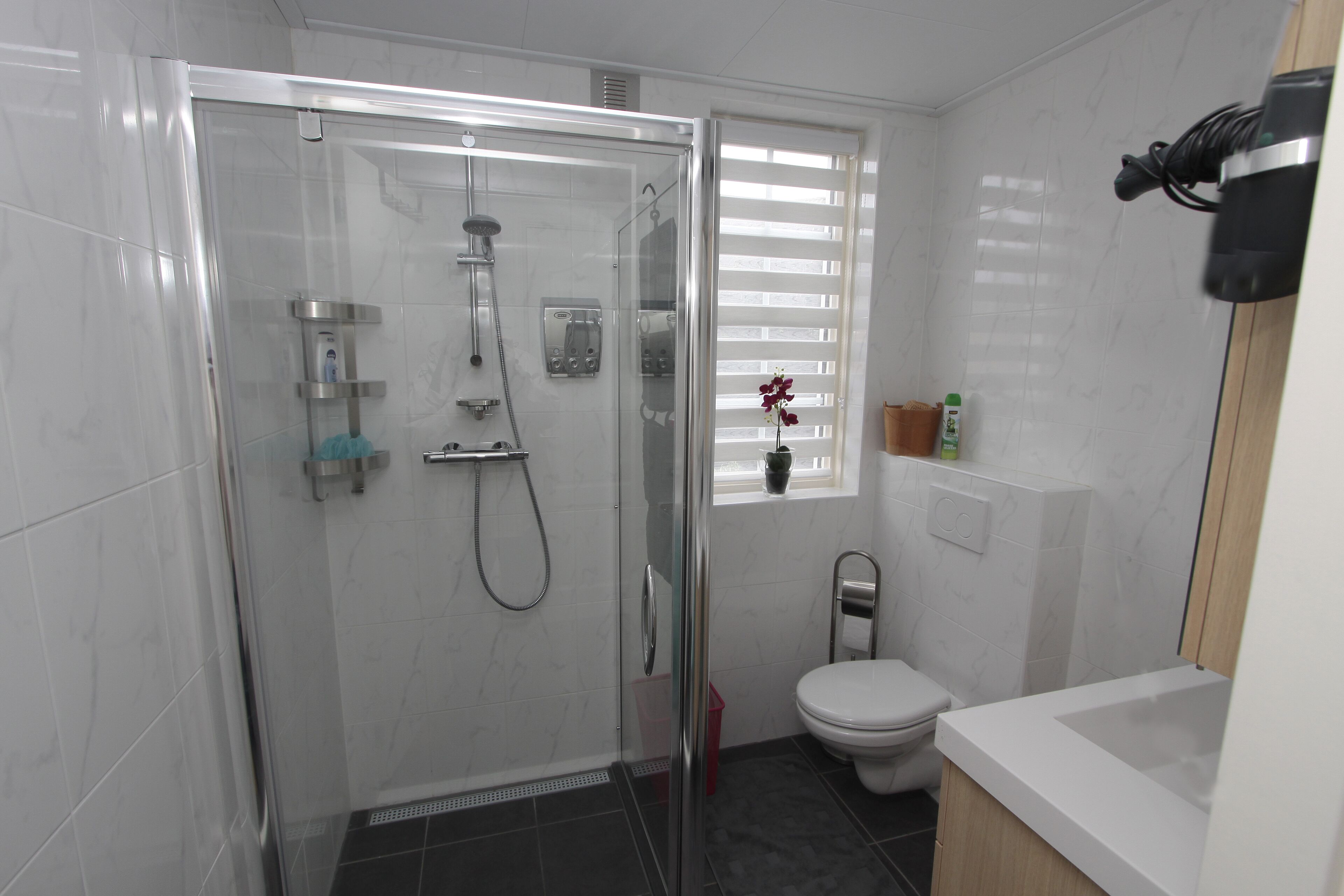 Un baño moderno con ducha de mampara de vidrio, inodoro y lavamanos.
