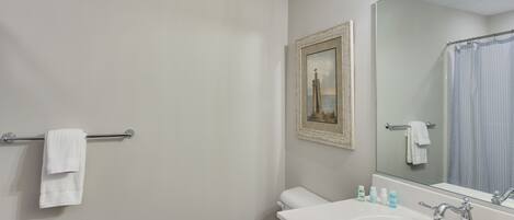 A bathroom with a white toilet, a sink with two faucets, a mirror, and a towel rack.