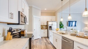 A modern kitchen with white cabinets, stainless steel appliances, and a marble countertop.