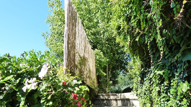 Un escalier en pierre, entouré d’une végétation luxuriante et de plantes en fleurs.