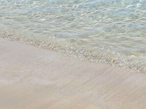 A sandy beach with clear shallow water.