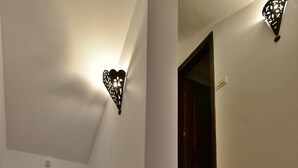 A staircase with red tiles and a white wall with a heart-shaped light fixture. - Ktima Grammeno Villa (Gialos)