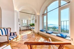 Ein geräumiges Zimmer mit großem Fenster und schöner Aussicht, eine gemütliche Sitzecke mit gestreiften Stühlen und einer hölzernen Bank.