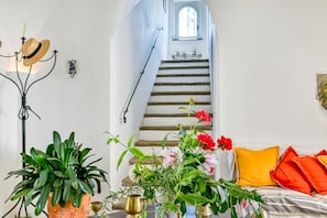 Une pièce avec un escalier, une plante en pot et un vase rempli de fleurs.