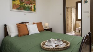 A neatly made bed with a green bedspread, two pillows, and a tray with two cups of coffee and a plate of cookies. - SAMAREITIDOS LIGHT STUDIO  - GREEN (Anafotia)