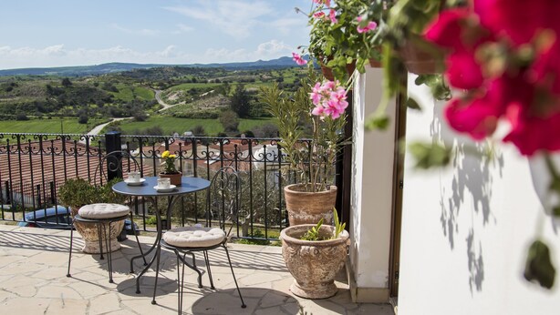 A balcony with a table and chairs, potted plants, and a view of the countryside. - SAMAREITIDOS LIGHT STUDIO  - GREEN (Anafotia)