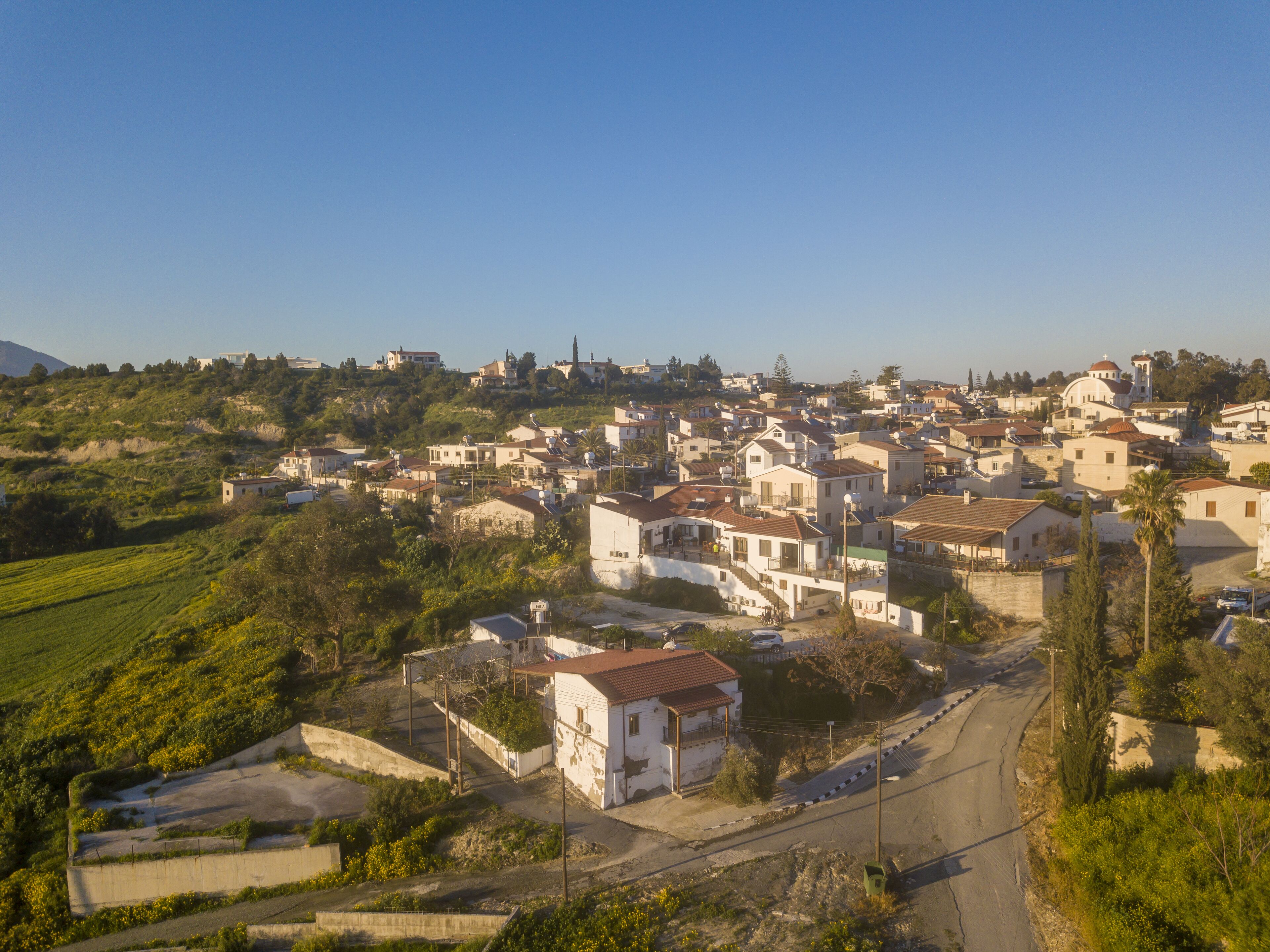 A hillside village with traditional architecture, narrow roads, and scattered greenery.