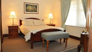 Una camera da letto ordinata con un letto grande, due comodini con lampade, una panca, un quadro appeso alla parete e una finestra con tende.