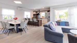 Ein modernes Wohnzimmer mit einem grauen Sofa, einem Essbereich mit Tisch und Stühlen sowie einer Küche mit Kochinsel.