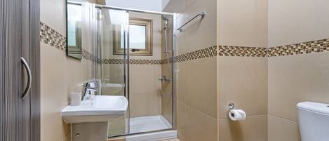 A modern bathroom with a glass-enclosed shower, a sink, and a toilet.