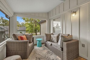 A sunroom with wicker furniture, a small table, and a view of the outdoors. - The Oriole, hot tub, walk or Bike to Saugatuck! (Saugatuck)