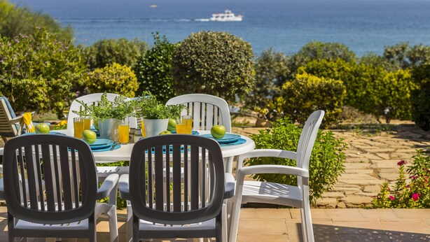 A table set for two with chairs, a potted plant, and a glass of orange juice. - Sirina Lina Beachfront Suite (Protaras)