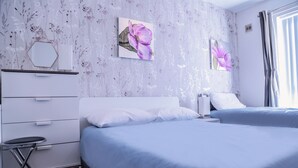 Ein modernes Schlafzimmer mit zwei Betten, einem Schminktisch und einem kleinen Hocker.