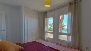 A bedroom with a bed, a wardrobe, and a window with a view of trees.