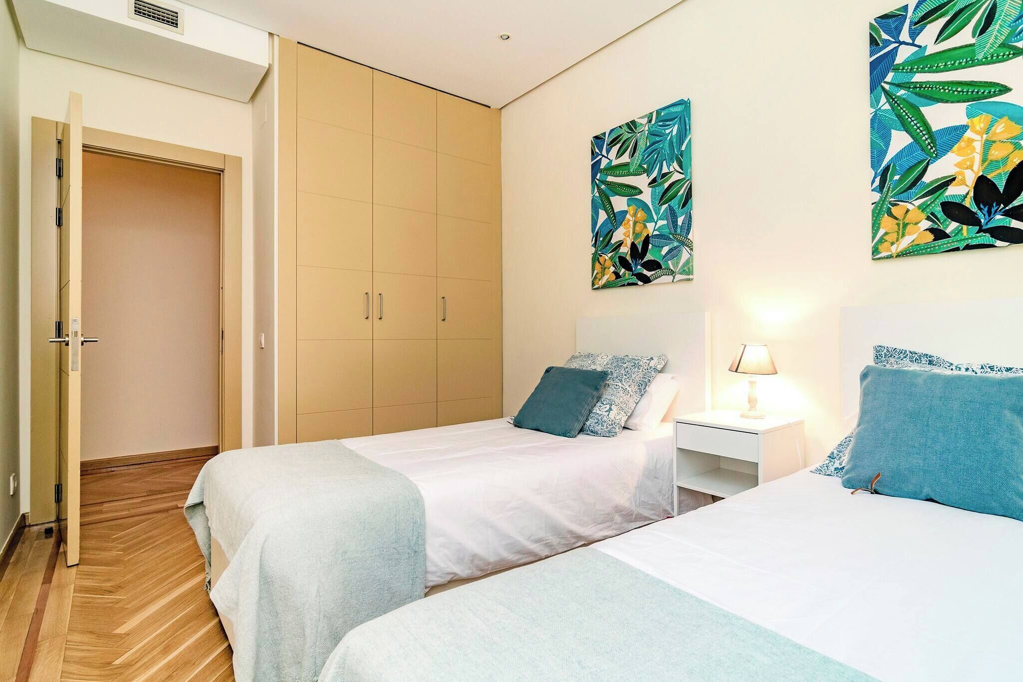 Une chambre d’hôtel avec deux lits, une armoire et deux tableaux accrochés au mur.