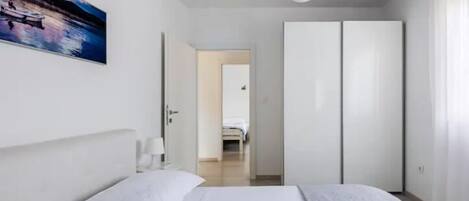 Un dormitorio moderno con cama, mesita de noche, un cuadro y un armario.