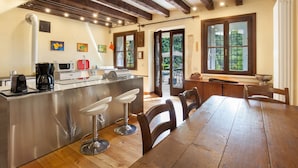 A modern kitchen with a central island, stainless steel appliances, and wooden dining table with chairs. - Il Giardino di Sibilla With Pool (Castelgomberto)