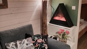 A cozy room with a grey sofa, a decorative wall with a mounted animal head, a fireplace, and a small table with a vase of flowers. - Studio with mountain corner 1 (AVORIAZ)