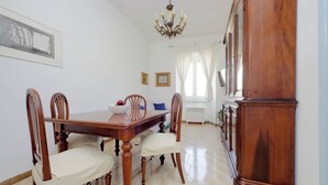 A dining area with a wooden table and chairs, a chandelier, and a large wooden cabinet. - Red House Rome - Trastevere (Roma)