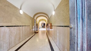 A long, narrow hallway with marble floors and walls, featuring a series of arches and a central light fixture. - Red House Rome - Trastevere (Roma)
