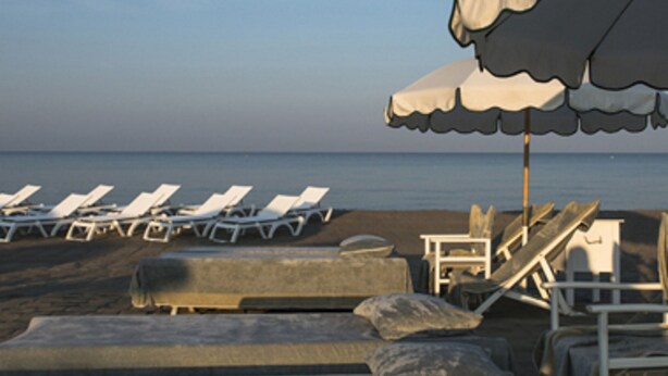 Ein Strand mit Reihen von Liegestühlen und Sonnenschirmen.