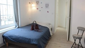 A bedroom with a bed, a chair, a wall with butterfly decals, and a door leading to another room. - L'Échappée belle - Dieppe (Dieppe)