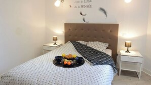 A neatly made bed with a patterned bedspread, a tray of fruit, and a wall with a motivational quote. There are two bedside tables with lamps. - L'Échappée belle - Dieppe (Dieppe)