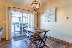 Enjoy meals at the dining table with benches, surrounded by a beautiful painting and natural light pouring in through the sliding glass door.