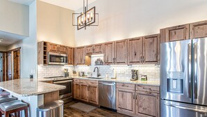 Une cuisine moderne avec des meubles en bois, des appareils en acier inoxydable et un plan de travail en marbre.
