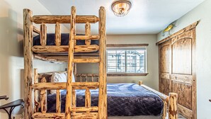 Un lit superposé avec une échelle, une fenêtre donnant sur un beau paysage et une armoire en bois.