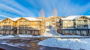 Un quartier résidentiel avec de nombreuses maisons à deux étages, une rue recouverte de neige et un ciel dégagé.