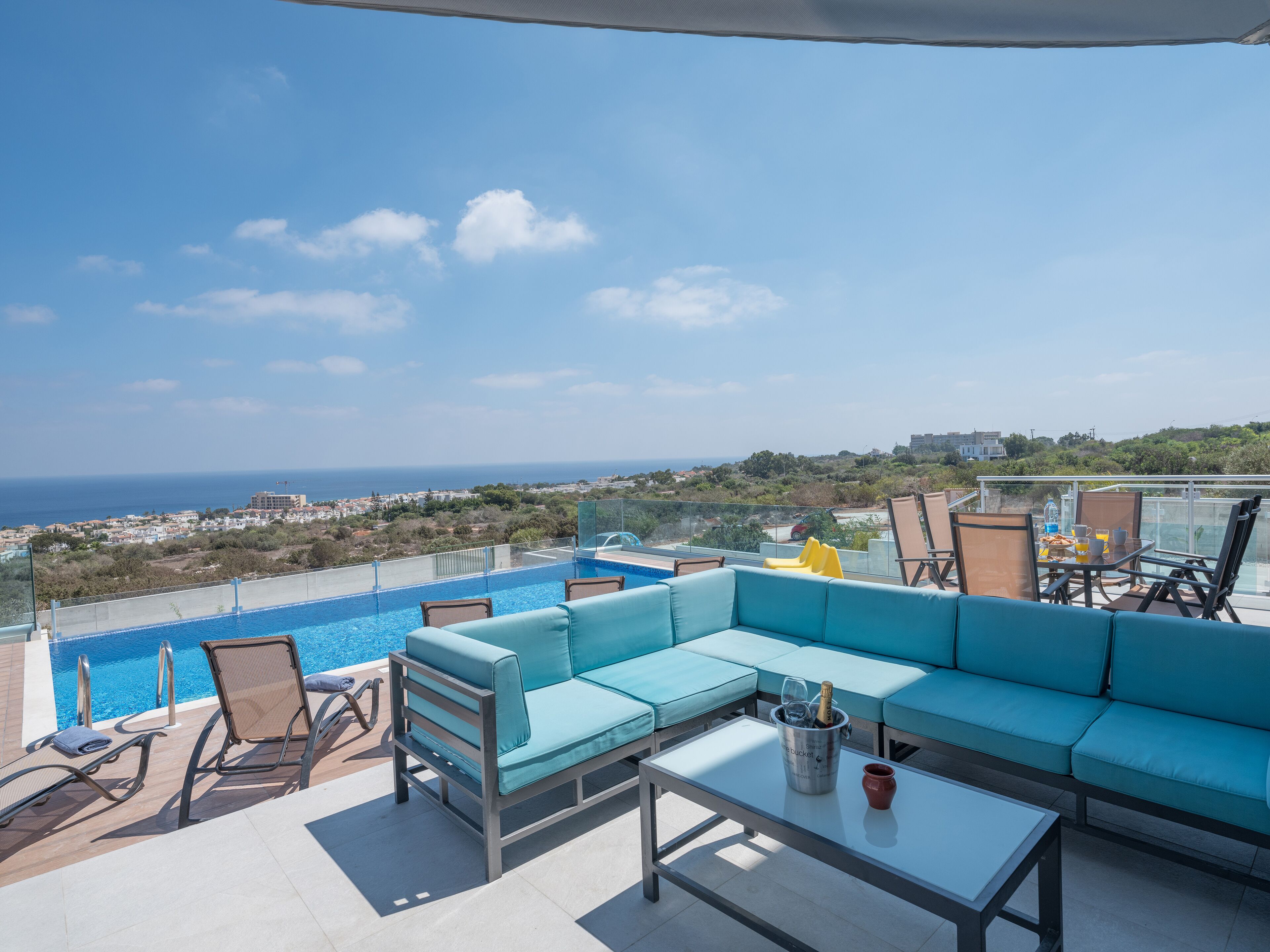 A rooftop terrace with a pool, seating area, and a clear view of the city and sea.