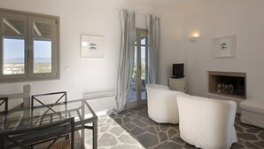 A living room with a glass table, white sofas, a fireplace, and a TV. - Kallisti Daphne  · Gorgeous Villa - an oasis for 8 (Santa Maria)