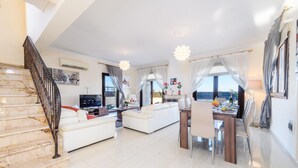 A spacious living area with a staircase, a dining table, and a sofa. - Hann's Villa - Charming Kapparis Getaway (Protaras)