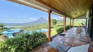 A covered outdoor area with a pool, seating, and a view of a mountain.
